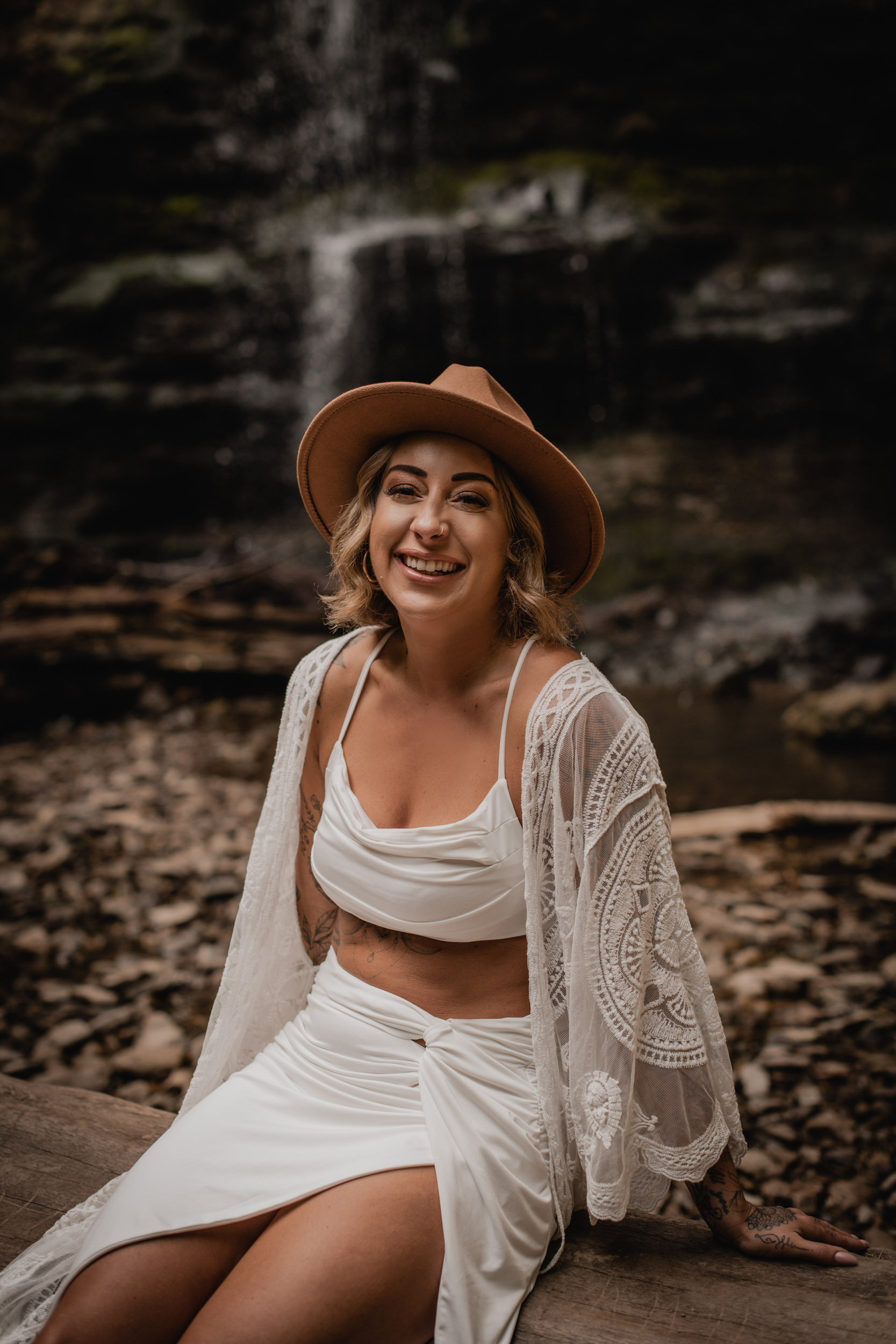 woman laughing in front of waterfall